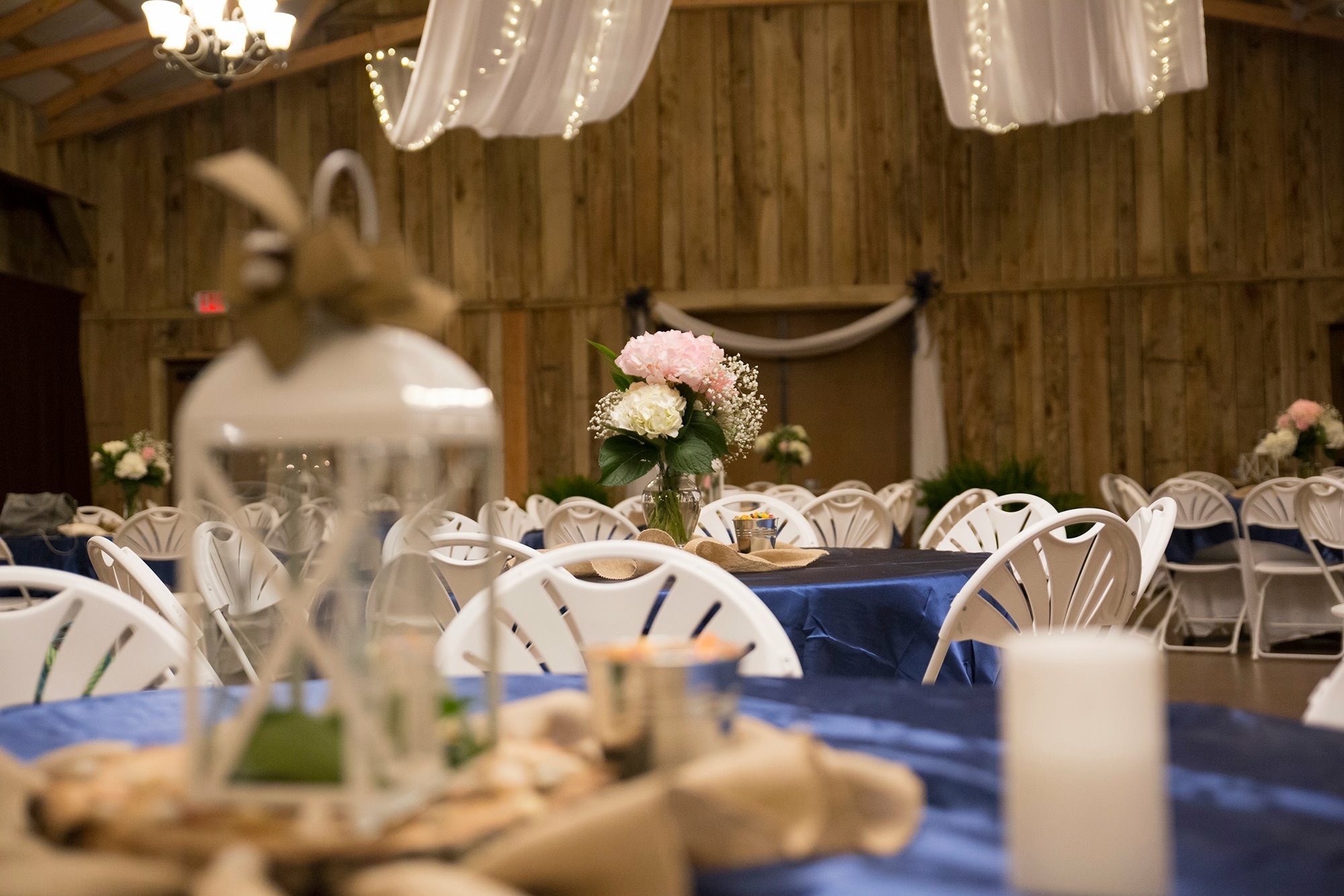 Elegant banquet hall setup featuring blue tablecloths, floral centerpieces, and white chairs, ideal for a wedding or special event.
